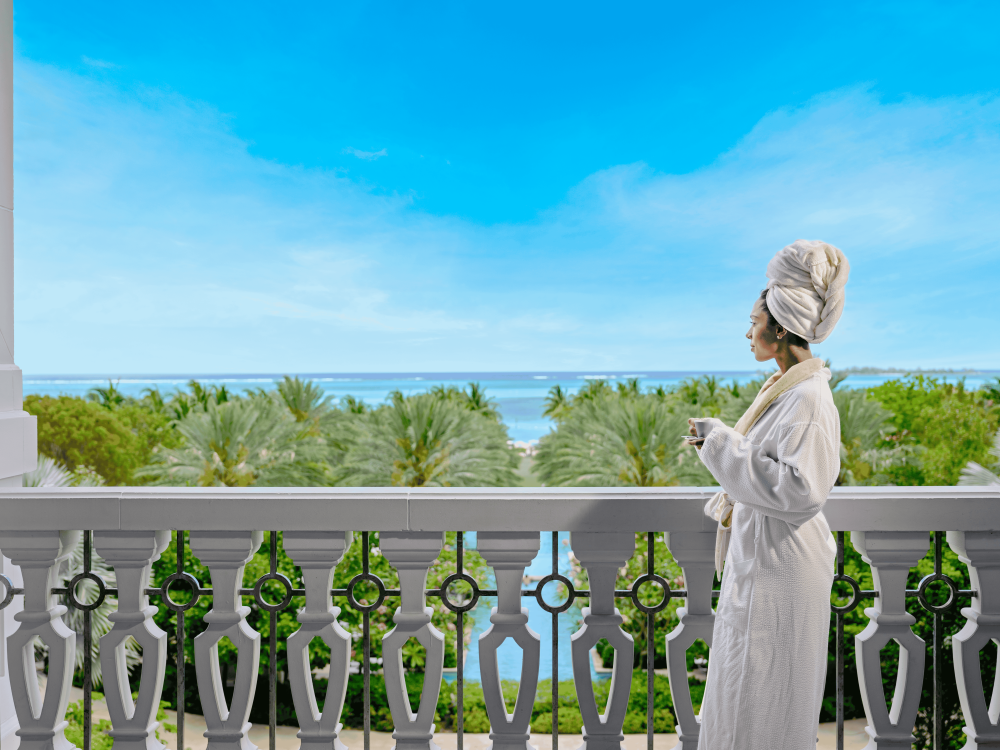 woman in robe looking out at the ocean from hotel 